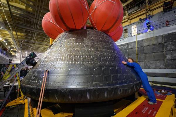 NASA astronaut Christina Koch, Artemis II mission specialist, hugs the Orion spacecraft aboard the USS John P. Murtha, following the spacecraft’s April 11 splashdown in the Pacific Ocean off the California coast.