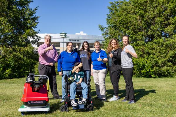 Sam Roberts with members of his care team and UK Pigman College of Engineering student Audra Proffitt, who helped design his custom football-throwing device.