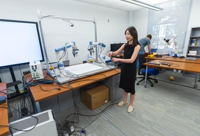 Xie in lab with robotic arms 